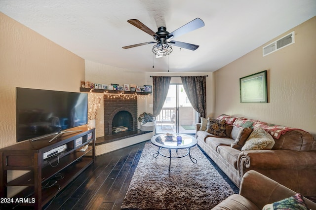 living room featuring a brick fireplace, dark wood-type flooring, and ceiling fan