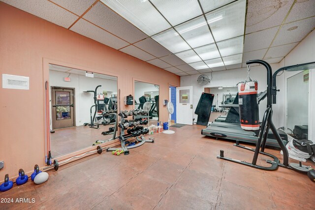 workout room featuring a paneled ceiling and tile patterned floors