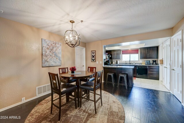 dining room with an inviting chandelier, a textured ceiling, and hardwood / wood-style flooring