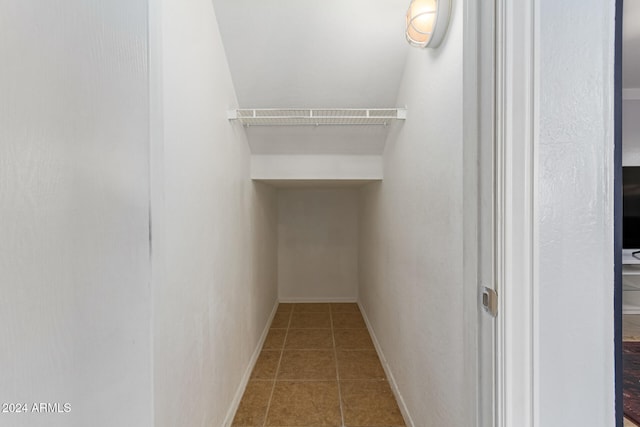 walk in closet with tile patterned flooring and lofted ceiling