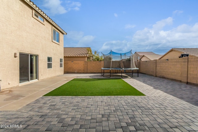 view of yard with a trampoline and a patio area