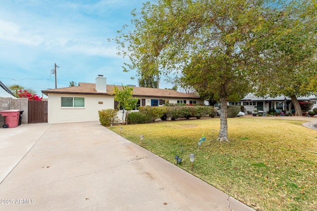 ranch-style house with concrete driveway, a front lawn, a chimney, and fence