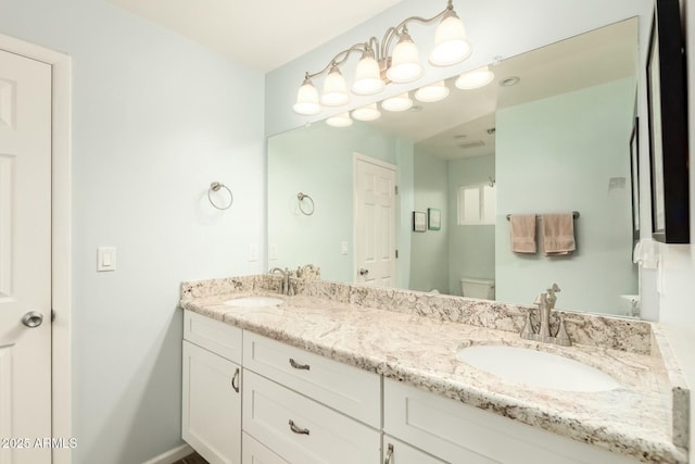 bathroom featuring toilet, double vanity, baseboards, and a sink