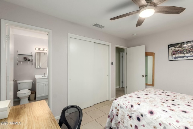 bedroom featuring light tile patterned floors, a closet, visible vents, ensuite bathroom, and a sink