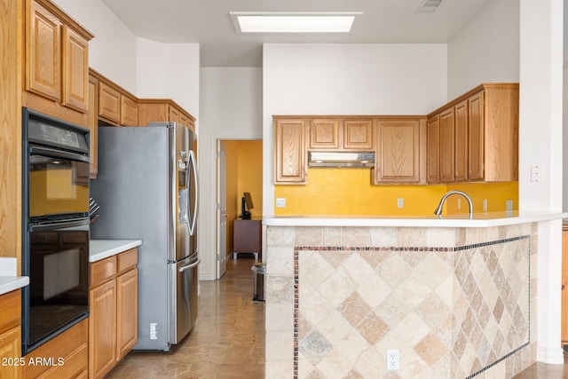 kitchen featuring double oven, sink, and stainless steel refrigerator