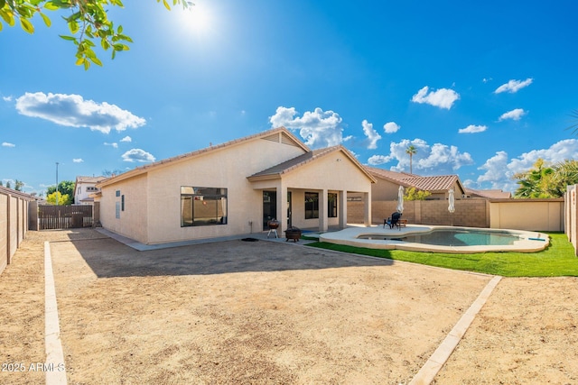 rear view of property with a fenced in pool and a patio area