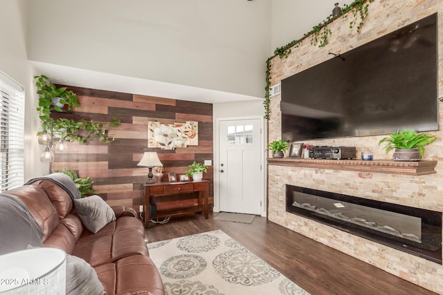 living room featuring a high ceiling, wood walls, and dark wood-type flooring