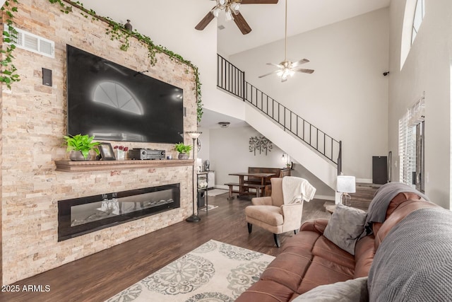 living room featuring ceiling fan, high vaulted ceiling, dark wood-type flooring, and a fireplace