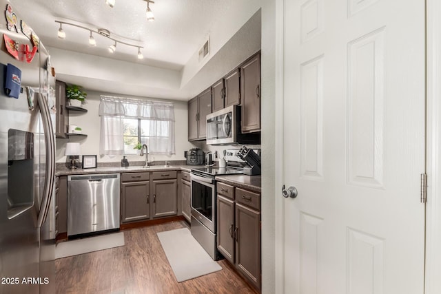 kitchen with sink, stainless steel appliances, dark stone countertops, and dark wood-type flooring