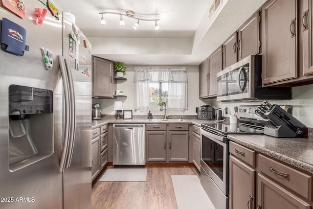 kitchen with sink, light hardwood / wood-style flooring, a textured ceiling, and stainless steel appliances