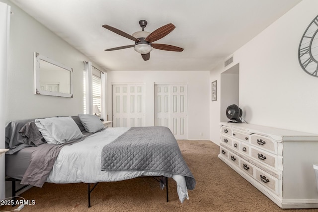 bedroom featuring ceiling fan, two closets, and carpet