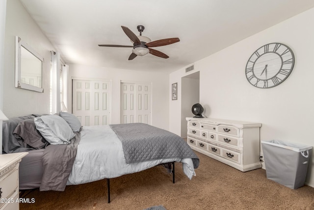 carpeted bedroom with two closets and ceiling fan