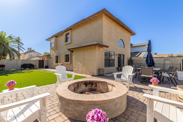 back of property with a fire pit, a patio area, and a yard