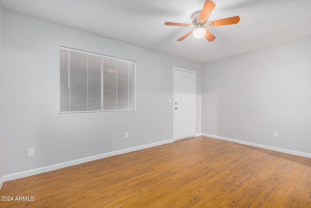 empty room with ceiling fan, baseboards, and wood finished floors