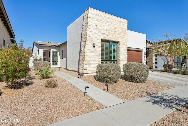 view of front of property featuring stone siding, concrete driveway, and stucco siding