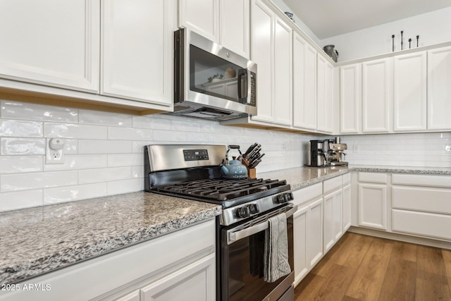 kitchen featuring white cabinetry, appliances with stainless steel finishes, decorative backsplash, and wood finished floors