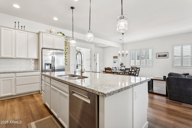 kitchen with stainless steel appliances, a sink, decorative backsplash, and wood finished floors