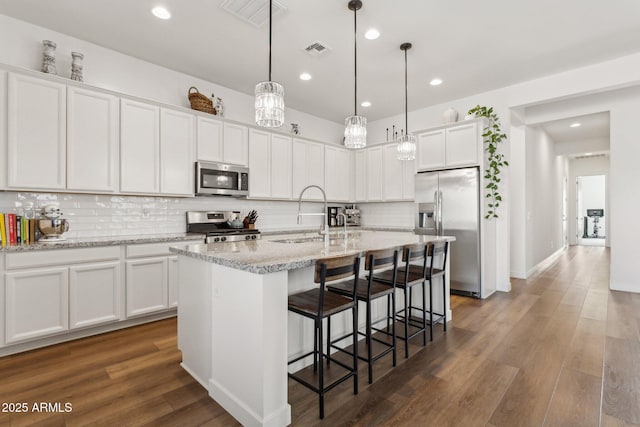 kitchen with dark wood-style floors, stainless steel appliances, a sink, and visible vents