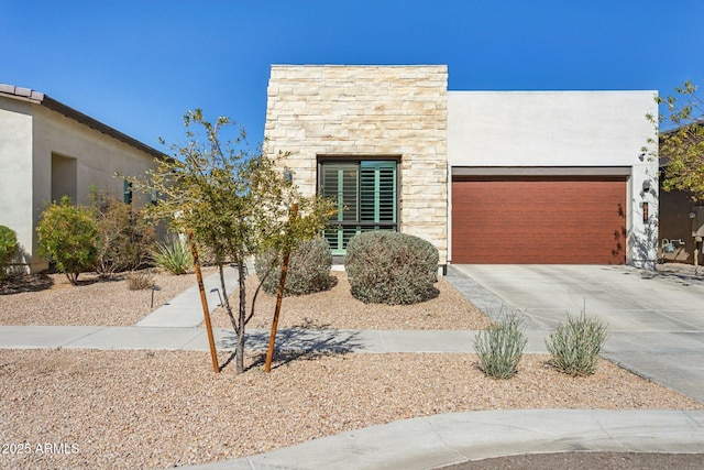 contemporary home featuring driveway, stone siding, a garage, and stucco siding