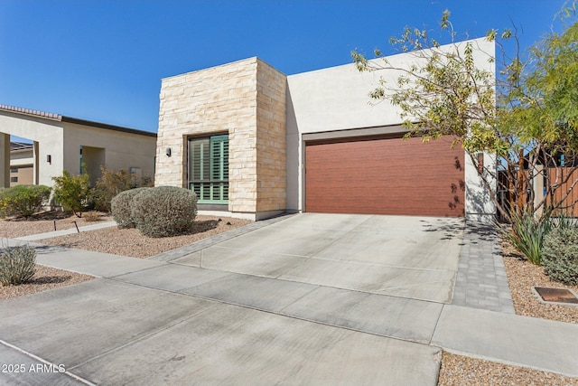 contemporary home featuring a garage, stone siding, and driveway