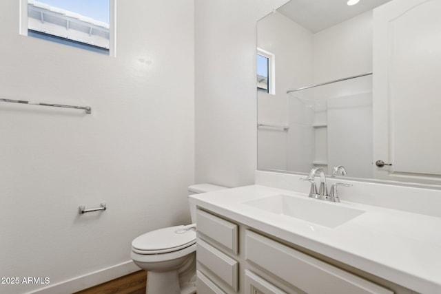 bathroom with toilet, baseboards, wood finished floors, and vanity