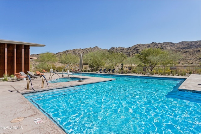 pool with a patio, fence, and a mountain view