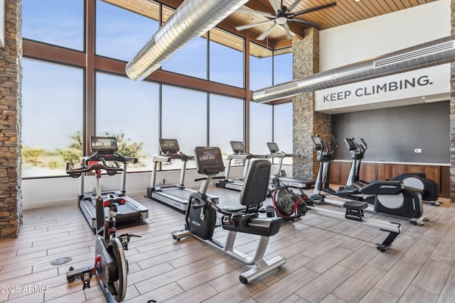 workout area featuring a ceiling fan, wood finish floors, wooden ceiling, and a towering ceiling