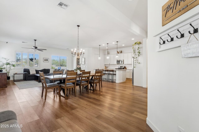 dining room with ceiling fan with notable chandelier, wood finished floors, visible vents, and recessed lighting