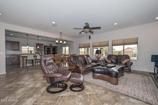 living room with ceiling fan with notable chandelier and a wealth of natural light