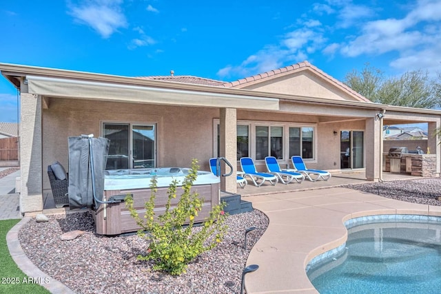 rear view of property featuring exterior kitchen, a patio, and a hot tub