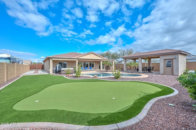 back of property with a fenced in pool and a patio