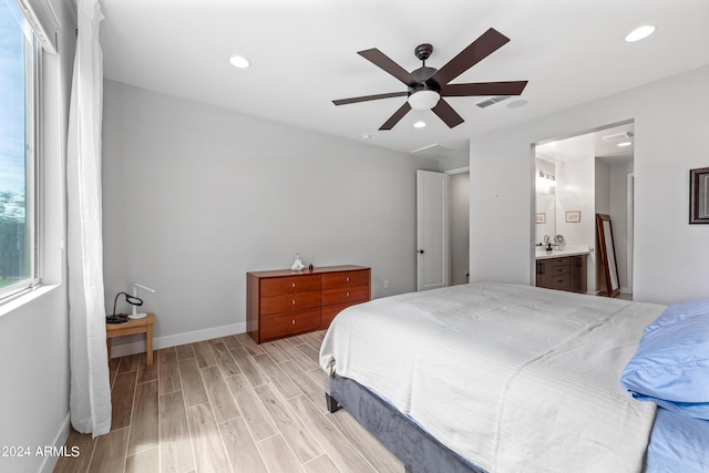 bedroom with sink, light hardwood / wood-style flooring, ensuite bathroom, and ceiling fan