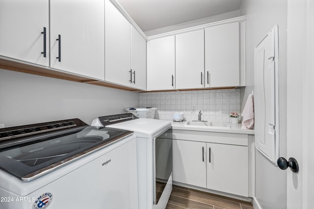 laundry room with sink, cabinets, washer and clothes dryer, and dark hardwood / wood-style flooring