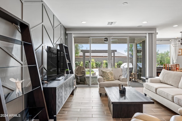 living room with plenty of natural light, a chandelier, and light hardwood / wood-style flooring