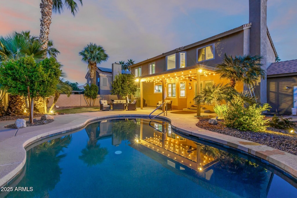 pool at dusk featuring outdoor lounge area and a patio area