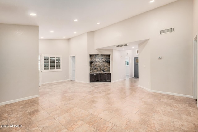 10244 N 65th Ln, Glendale, AZ 85302 - unfurnished living room featuring a towering ceiling, recessed lighting, baseboards, and a fireplace