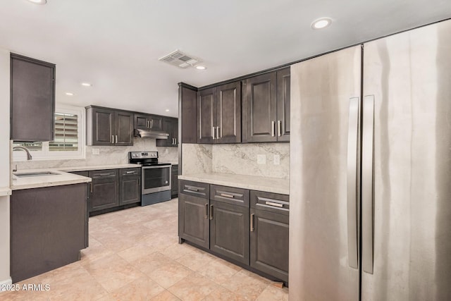 10244 N 65th Ln, Glendale, AZ 85302 - kitchen featuring appliances with stainless steel finishes, a sink, under cabinet range hood, tasteful backsplash, and recessed lighting