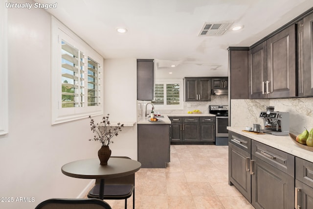 10244 N 65th Ln, Glendale, AZ 85302 - kitchen featuring stainless steel range with electric cooktop, tasteful backsplash, under cabinet range hood, light countertops, and light tile patterned flooring