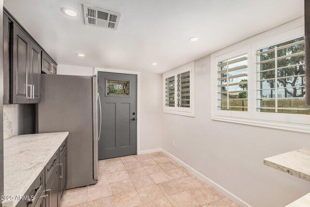 10244 N 65th Ln, Glendale, AZ 85302 - kitchen featuring freestanding refrigerator, light stone counters, baseboards, recessed lighting, and light tile patterned flooring