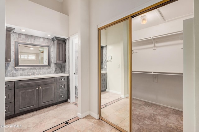 10244 N 65th Ln, Glendale, AZ 85302 - full bathroom featuring vanity, a walk in closet, toilet, tasteful backsplash, and baseboards