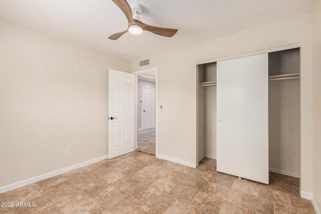 10244 N 65th Ln, Glendale, AZ 85302 - unfurnished bedroom featuring a closet, baseboards, ceiling fan, and stone finish floors