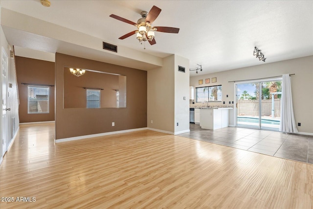 1520 E Flint St, Chandler, AZ 85225 - unfurnished living room featuring ceiling fan with notable chandelier, rail lighting, visible vents, baseboards, and light wood-style floors