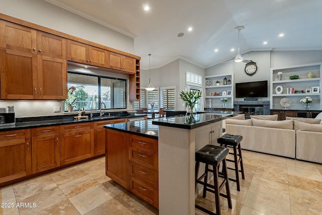 kitchen featuring sink, a breakfast bar, ornamental molding, a kitchen island, and decorative light fixtures