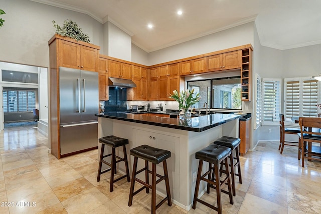 kitchen with stainless steel built in refrigerator, a kitchen island, a breakfast bar, and backsplash