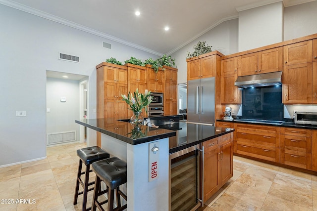 kitchen with a breakfast bar area, crown molding, built in appliances, a kitchen island, and beverage cooler