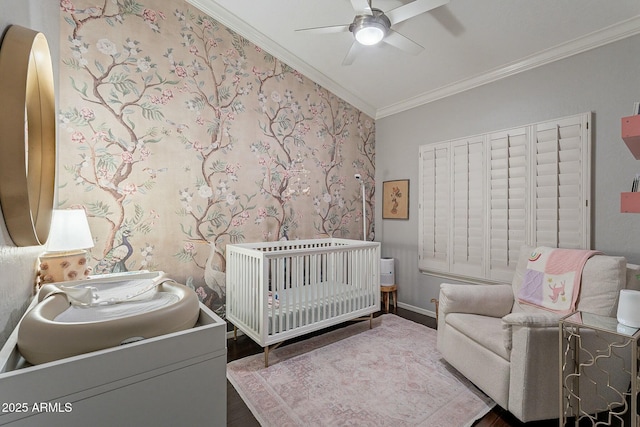 bedroom featuring a crib, crown molding, hardwood / wood-style floors, and ceiling fan