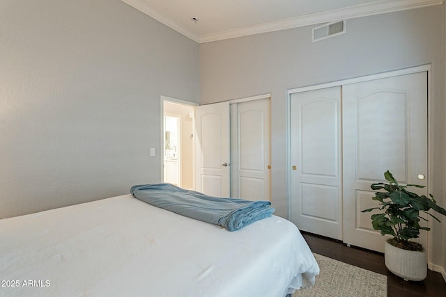 bedroom featuring multiple closets, ornamental molding, and dark hardwood / wood-style floors