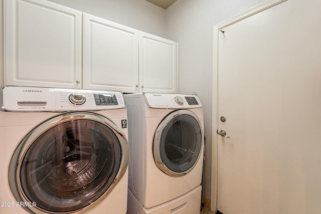 laundry room featuring washer and dryer and cabinets