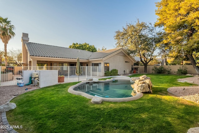 rear view of house featuring a fenced in pool and a yard