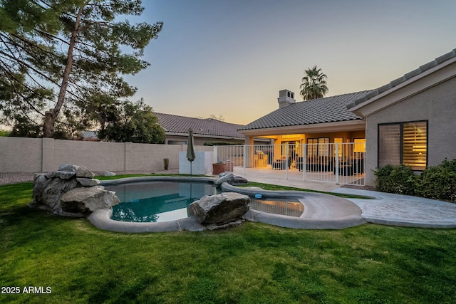 pool at dusk with a yard and a patio area